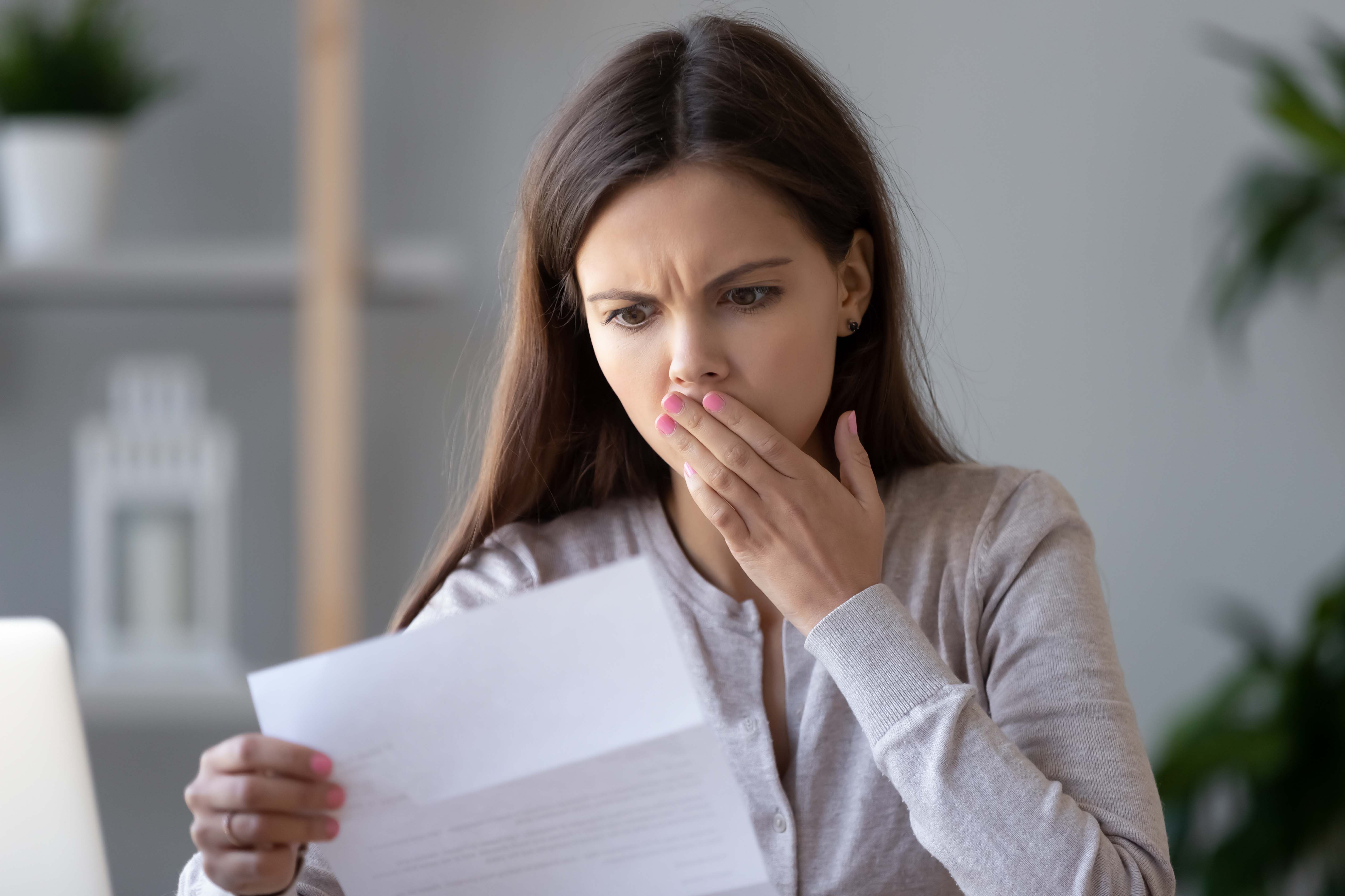 College student looking at college bill with shocked expression.

