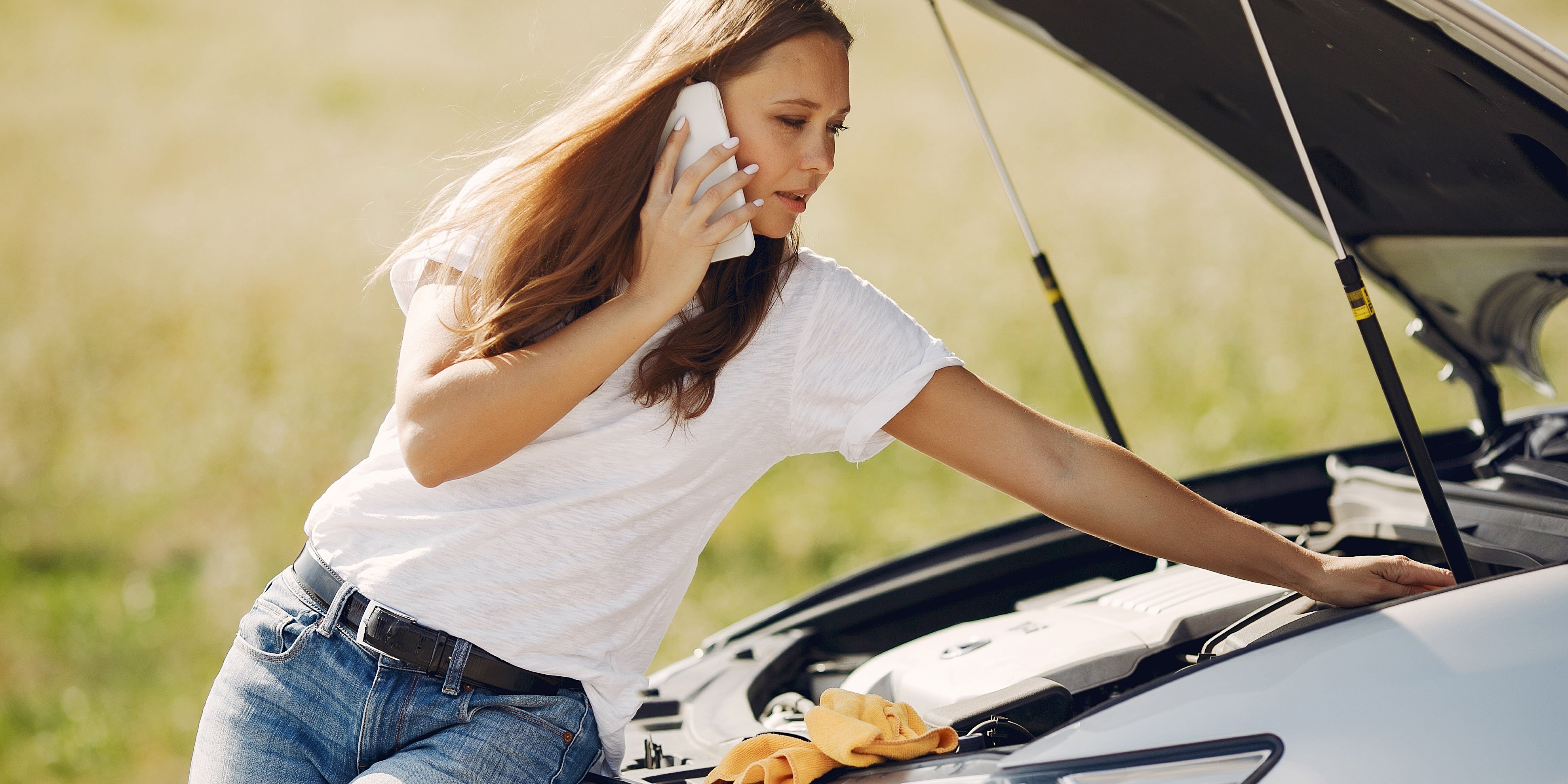 College student with hands on hips, frowning as she looks at her dented car