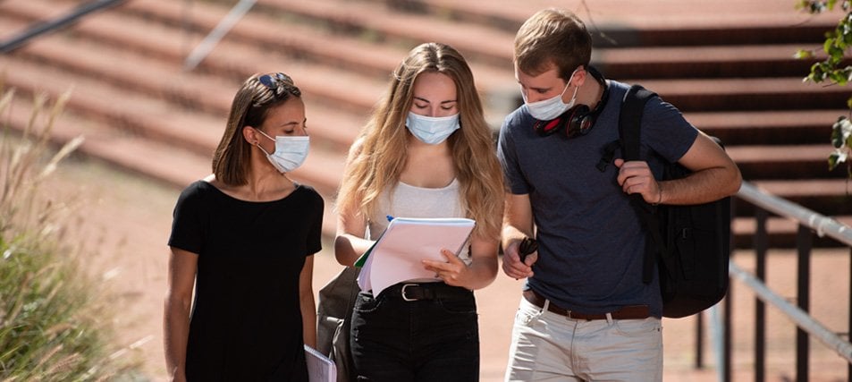 three students wearing masks on campus