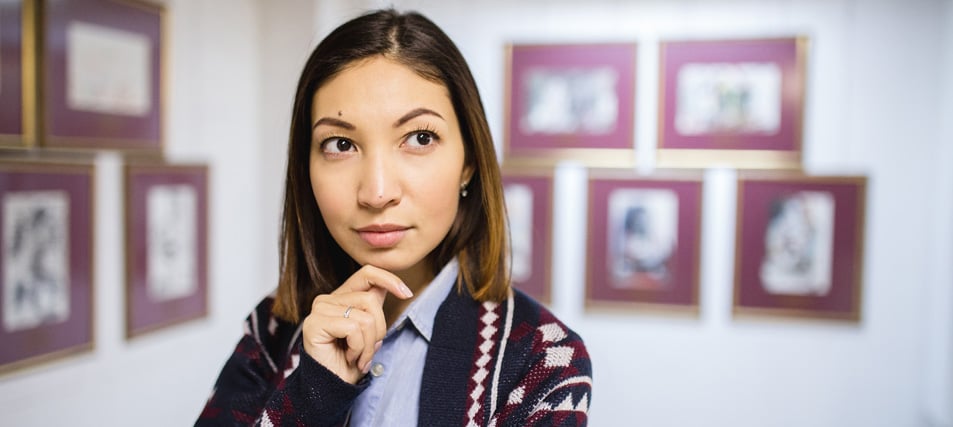 Female student looking thoughtfully at painting in museum