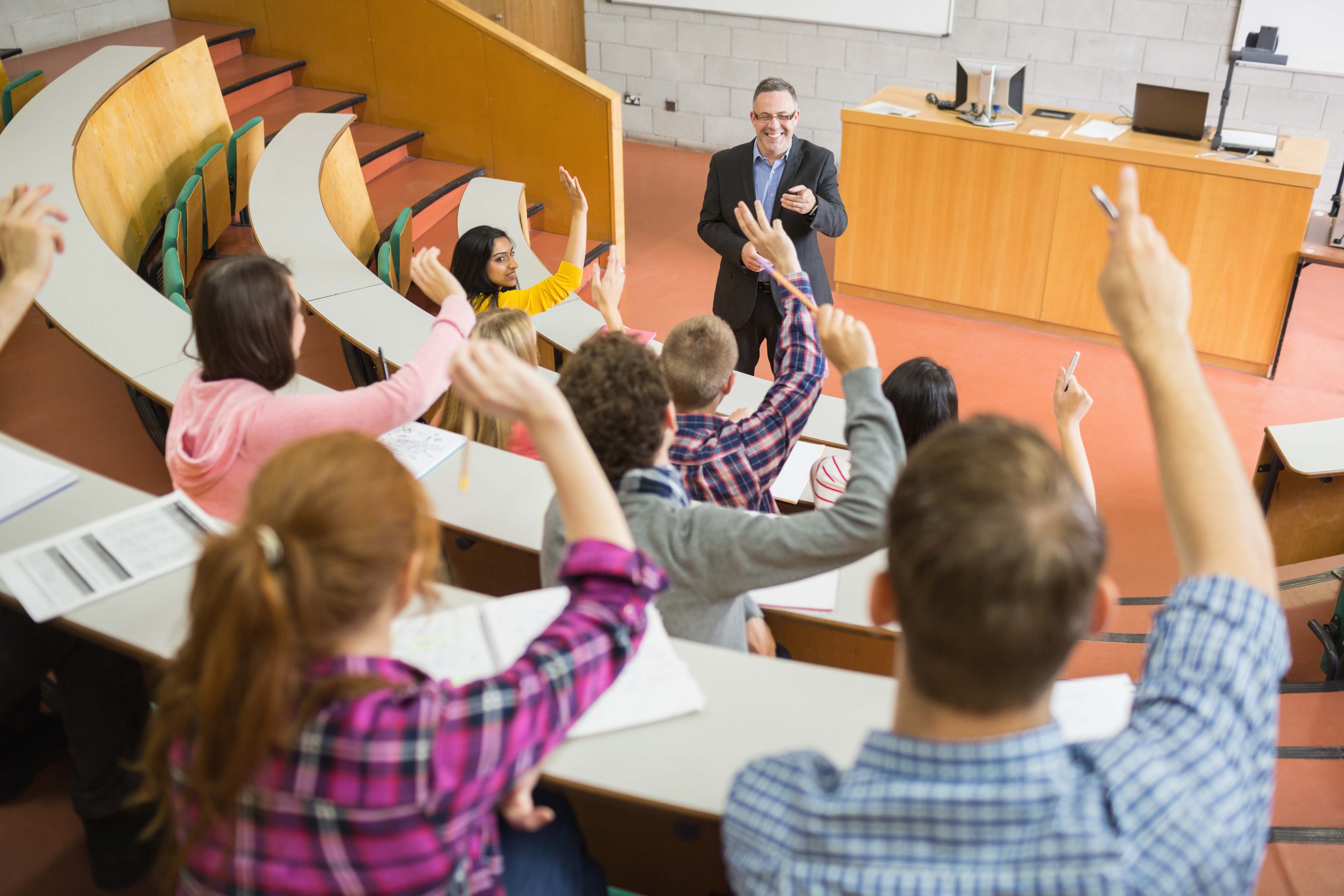 Professor addressing students inside a college lecture hall.
