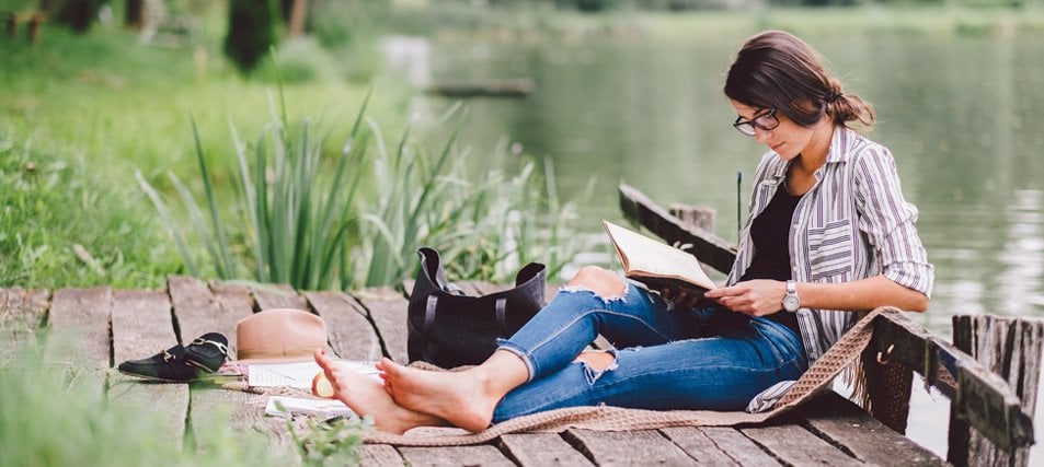 female student studying by a lake