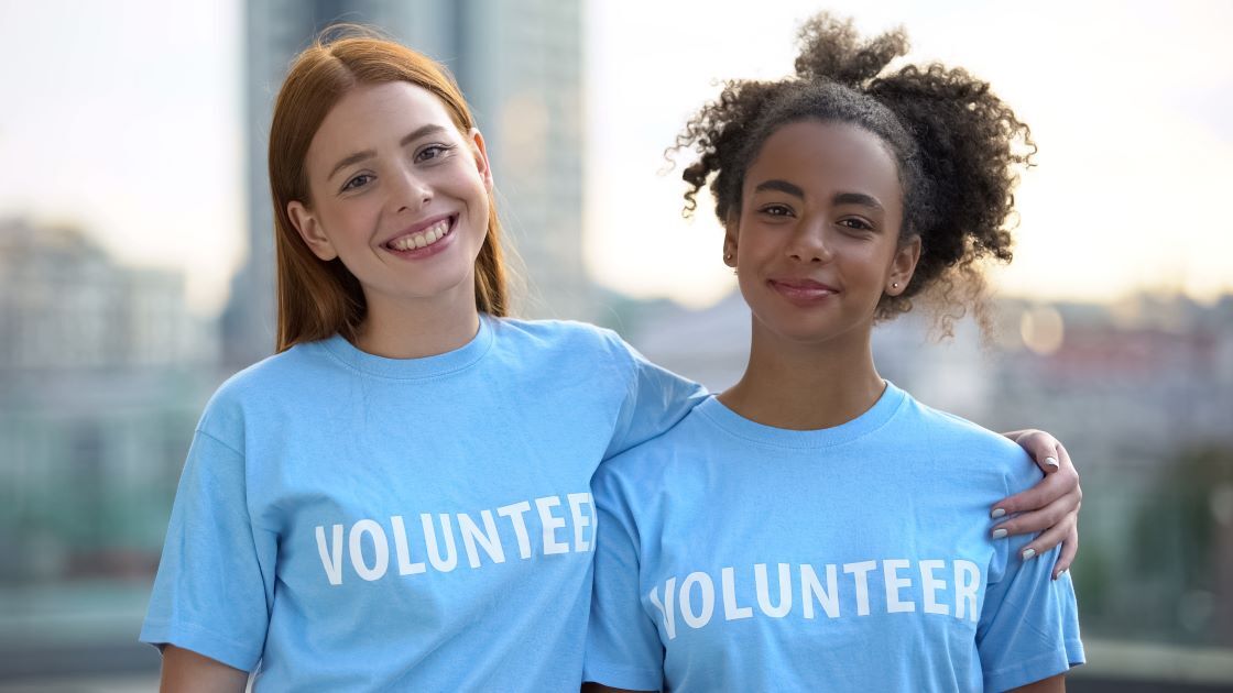 Two teenager girls wearing blue t-shirts with the word ‘volunteer’ on the front