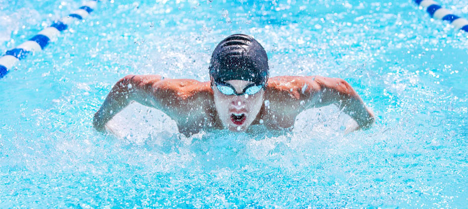 Competitive collegiate swimmer doing butterfly stroke in pool